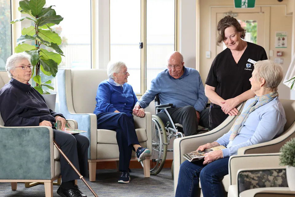 Residents and a care worker talking in a sitting room