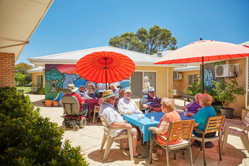 Residents sitting together under courtyard umbrellas