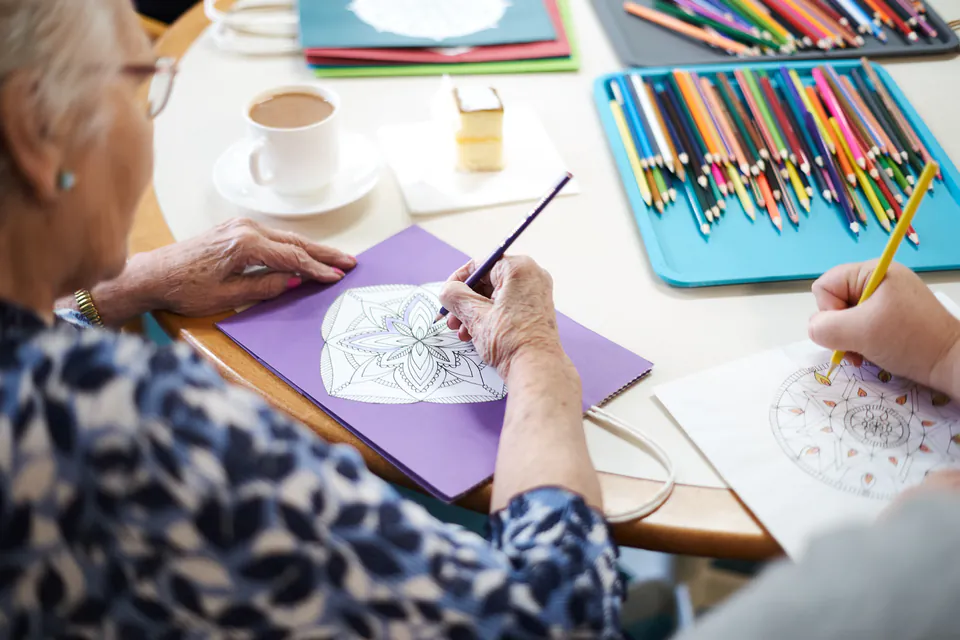 Residents drawing at a table with coloured pencils