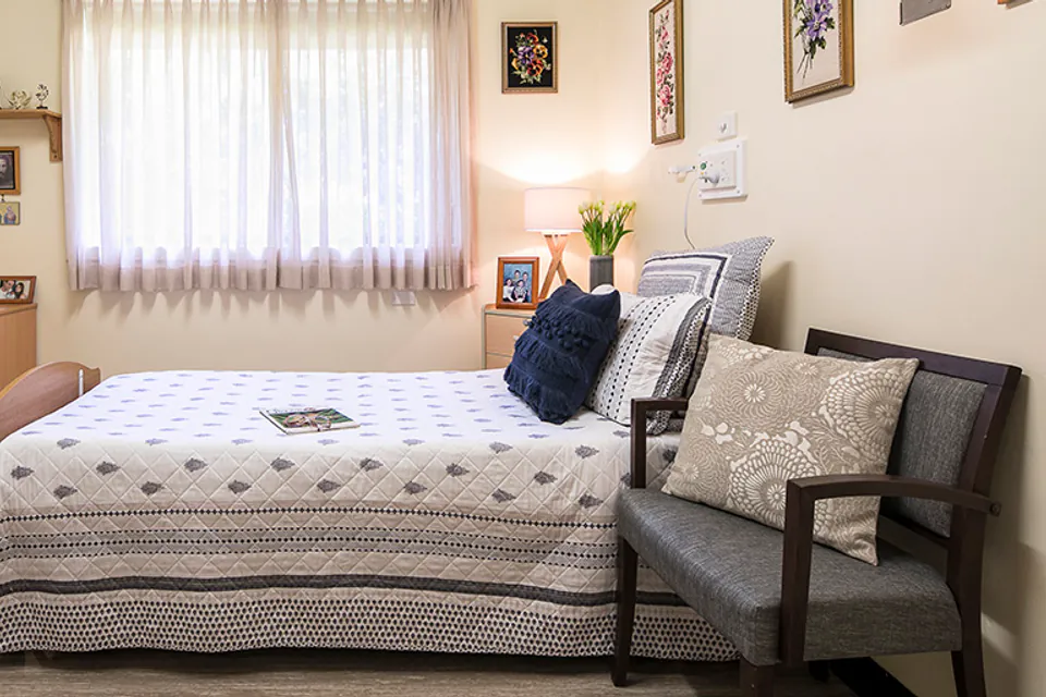 Bedroom with a single bed and armchair by a curtained window