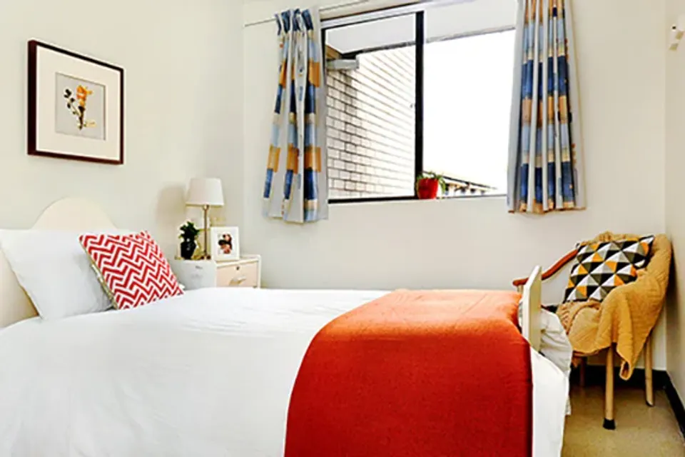 Bedroom with orange throw and armchair