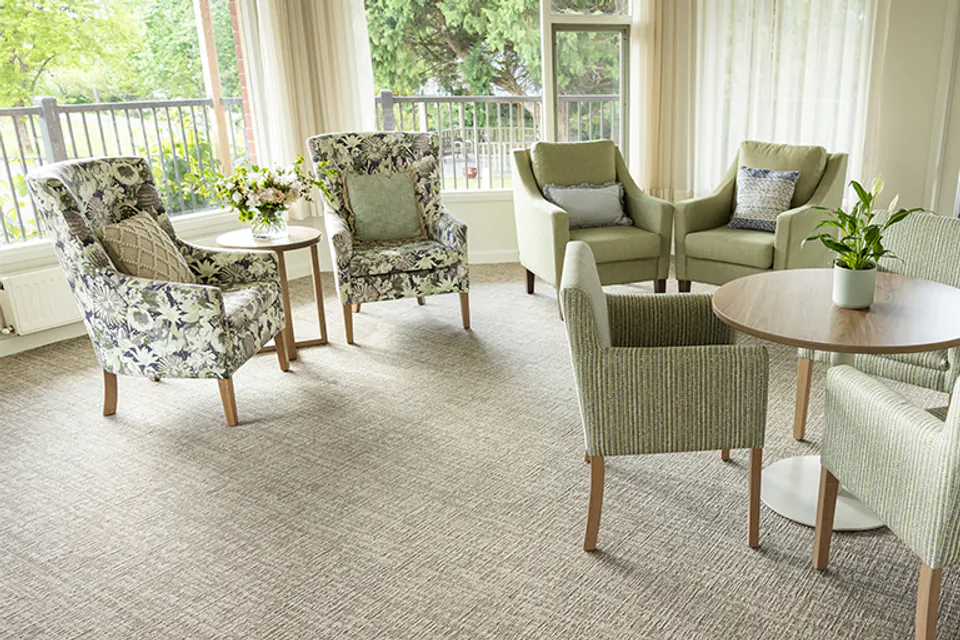 Sunlit lounge with upholstered chairs beside tall windows